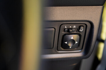 A close-up of the black electric side mirror control panel inside a car, showing the selector switch for L/R and the four-way directional pad © Haeruman