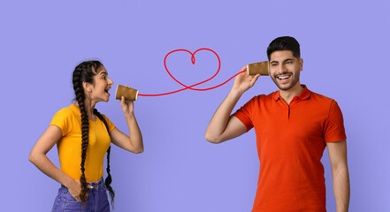Two friends enjoy a fun activity using homemade tin can telephones while standing against a colorful background. They share laughter, showing the joy of communication and connection.