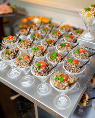 Individual quinoa salad servings displayed in elegant glass cups, garnished with cherry tomatoes and parsley, creating a colorful and fresh presentation for catering or events