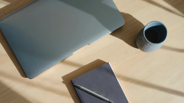 Modern workspace with laptop, notepad, and coffee cup on table  