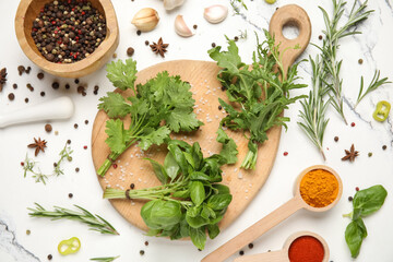 Composition with wooden cutting board, herbs and spices on marble background, closeup