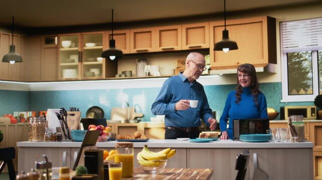 Elderly couple preparing a healthy breakfast with toast for a natural morning routine indoors. Mature husband and wife share casual conversation, creating positive household moment. Camera A.