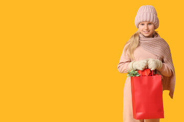 Cute girl with shopping bag on yellow background. Christmas celebration