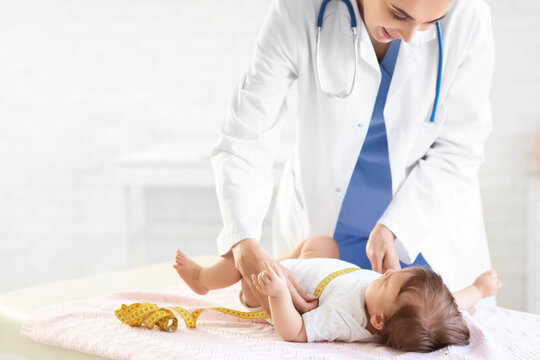 Female pediatrician measuring little baby on couch in clinic