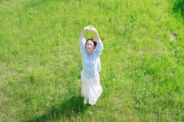 野原で伸びをする女性　俯瞰撮影
