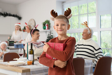 Cute little boy with gift box at Christmas dinner in kitchen