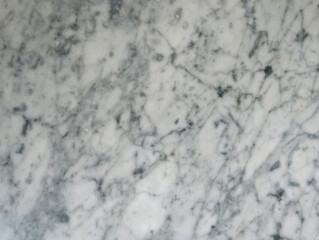 Close-up texture of natural white carrara marble slab with fine gray veining. Polished stone tile surface, classic and elegant textural pattern. Luxury flooring, countertops and interior cladding.