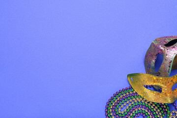 Colorful beads with carnival masks for Mardi Gras celebration on blue background