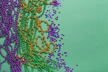 Colorful beads with sequins for Mardi Gras celebration on green background
