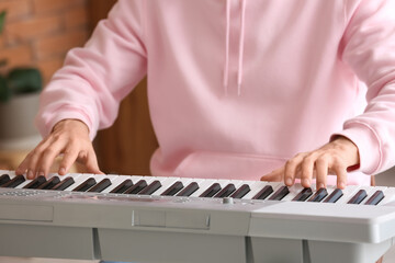Male musician playing synthesizer at home, closeup