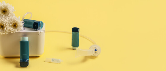 Modern nebulizer with inhalers and chrysanthemum flowers on yellow background