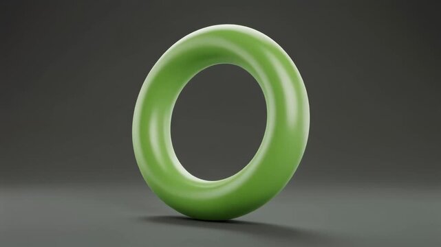 A smooth, glossy, light green, slightly irregular torus-shaped object stands on a dark grey surface with subtle reflections.