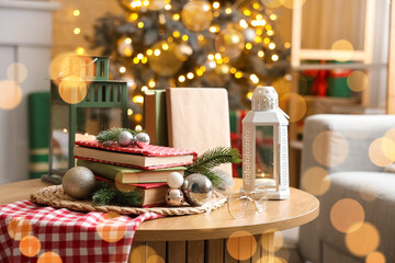 Books with Christmas balls and fir branches on table in room