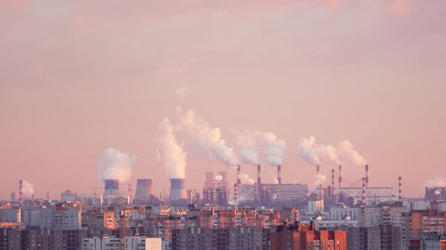 Industrial city skyline with power plant chimneys releasing steam into the air at sunset. Urban landscape with residential buildings and energy infrastructure. Concept of industry, environment, air qu