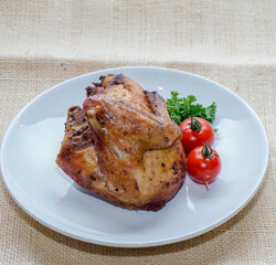 Roasted chicken breast quarter served with cherry tomatoes and parsley on white plate over rustic burlap background. Ideal for recipe blogs, menus, food advertising, and culinary content