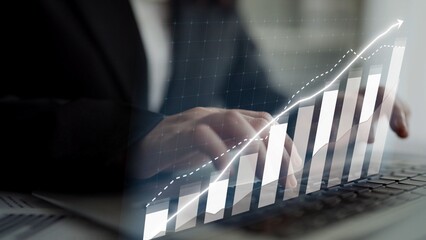 A business professional focuses on financial data using a laptop in an office. A chart overlay illustrates growth and success trends. Ideal for finance and business. Copula