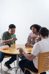 Diverse friends playing board game together at table