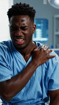 Young Black Man in Hospital Scrubs Experiencing Severe Shoulder Pain.