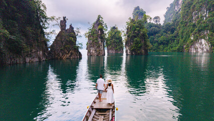 Naklejka premium Couple exploring the serene beauty of Cheow Lan Lake in Khao Sok, Thailand
