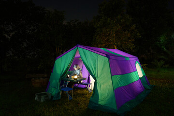 Nighttime camping tent in a forest clearing surrounded by nature