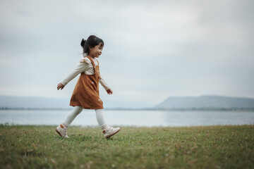 happy toddle girl walking on grass field near the river