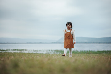 happy toddle girl walking on grass field near the river