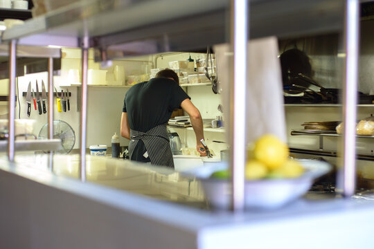 Looking through 'the pass' at a chef doing prep in a commercial kitchen - horizontal