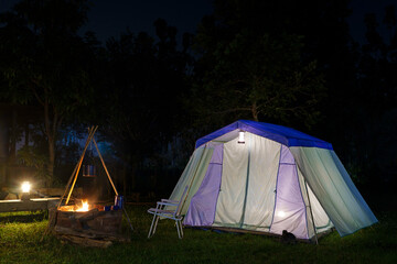 Nighttime camping tent in a forest clearing surrounded by nature