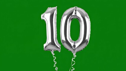Silver foil number 10 balloons floating with festive sparkles on a vibrant green background for anniversary celebration concept and milestone achievement
