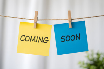 Photorealistic sticky notes 'COMING' and 'SOON' hanging on string with clothespins, set against a soft white bokeh background. Perfect for various themes.