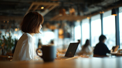 Young woman working on laptop in modern cafe with warm ambient light and shallow depth of field