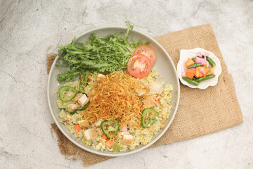 Indonesian Fried Rice with Chicken, Vegetables and Pickles on Rustic Table