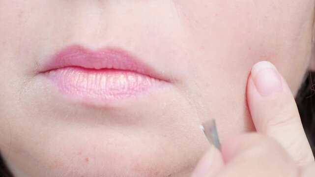 mature female lips, removes with metal tweezers excess facial hair, excessive hair growth, problem depilation on face, hormonal disorder during menopause