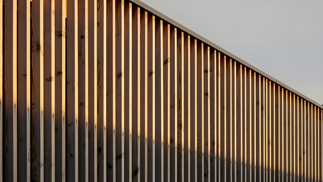 Modern Wooden Slat Wall Exterior Facade with Dramatic Sunlight Shadow Play Sustainable timber construction facade detail