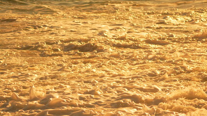 Ocean Waves Sunset Golden foamy ocean waves reflecting warm light at dusk, creating a beautiful shimmering scene.