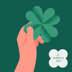 Hand holding four-leaf clover for St. Patrick's Day