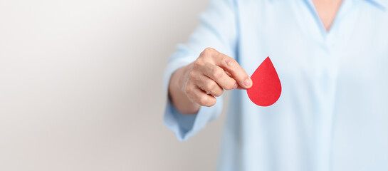 Elderly woman with red Blood drop paper for concept of June World Blood Donor day, Donation, January Blood donor awareness month, April Hemophilia awareness day, May Thalassemia Day, Anemia awareness
