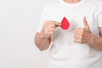Elderly woman with red Blood drop paper for concept of June World Blood Donor day, Donation, January Blood donor awareness month, April Hemophilia awareness day, May Thalassemia Day, Anemia awareness