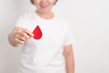 Elderly woman with red Blood drop paper for concept of June World Blood Donor day, Donation, January Blood donor awareness month, April Hemophilia awareness day, May Thalassemia Day, Anemia awareness