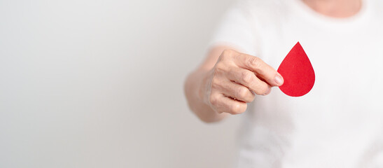 Elderly woman with red Blood drop paper for concept of June World Blood Donor day, Donation, January Blood donor awareness month, April Hemophilia awareness day, May Thalassemia Day, Anemia awareness
