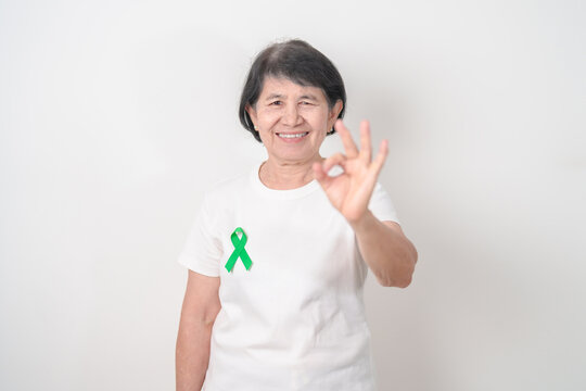 Elderly with Green Ribbon for concept of July Eye Injury Prevention month, January Glaucoma Awareness month, February Gallbladder and Bile duct and October Liver cancer. Health and world cancer day - Powered by Adobe
