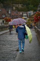 Asiatischer Tourist mit zwei Regenschirmen auf der alten Mainbr&uuml;cke in W&uuml;rzburg
