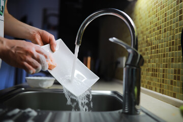 Man washing dish in sink at restaurant.People are washing the dishes too Cleaning solution