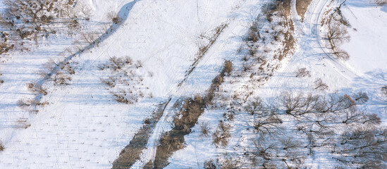 winter landscape at sunny day. thin layer of snow on ground. bare trees with long shadows. panoramic aerial view.