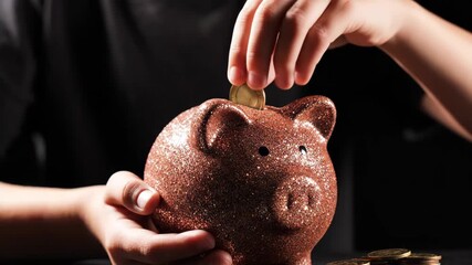 Coin Insertion into Glittery Piggy Bank - A close-up video of hands placing a coin into a sparkling glitter-covered piggy bank.