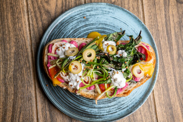 Gourmet toast. Nutrition food. Artisan bread with olive green leaves meat on plate. Portion meal with dripping bright sauce mustard.