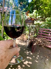 A hand holding a glass with red wine with a bbq fire burning in the background