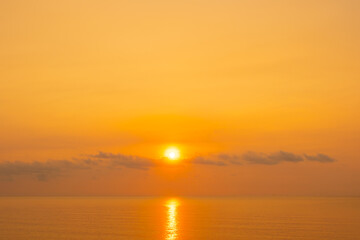 Fototapeta premium Nature sky breathtaking golden sunset over a calm ocean, with the entire sky and water bathed in brilliant shades of yellow and orange. Streaky clouds enhance the dramatic display of light 