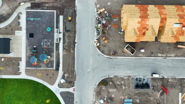Suburban housing construction site alongside a recreation area then farm fields - straight down aerial view