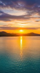 Obraz premium Golden sunset over calm lake and rolling hills